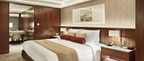 A hotel room with a large bed, a desk, a chair, and a mirror.
