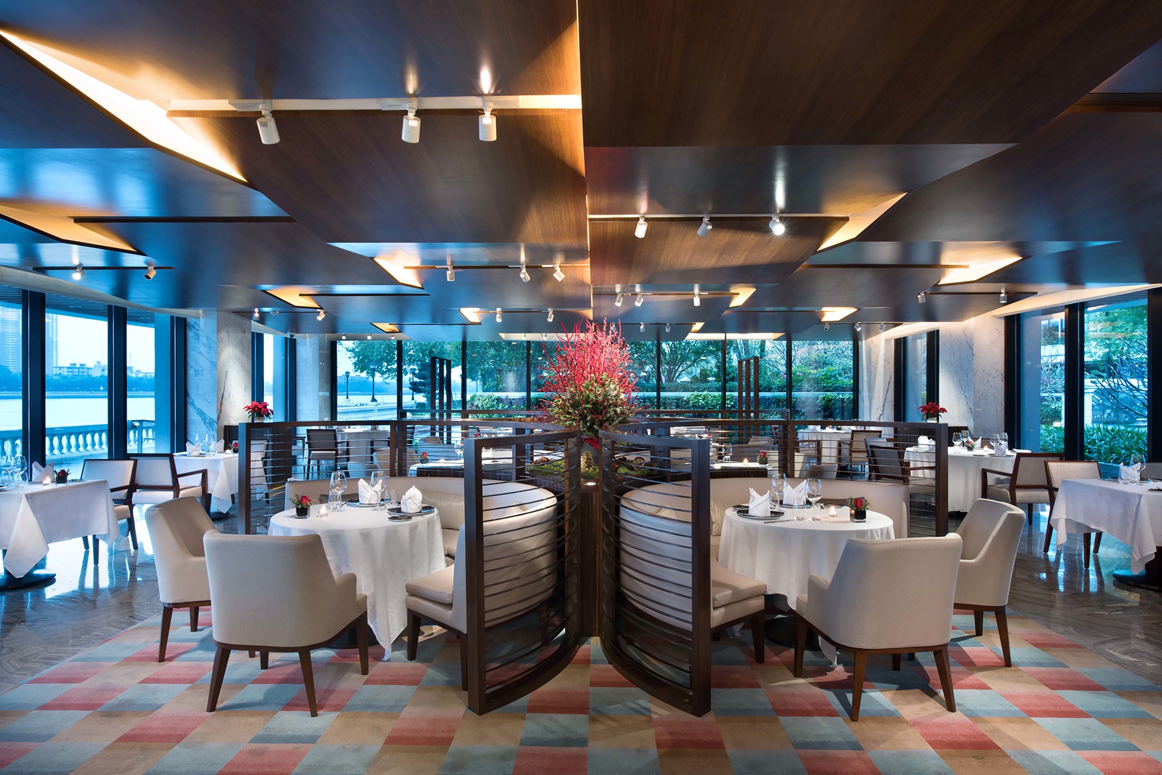 A modern restaurant with a central floral arrangement, round tables, and chairs.