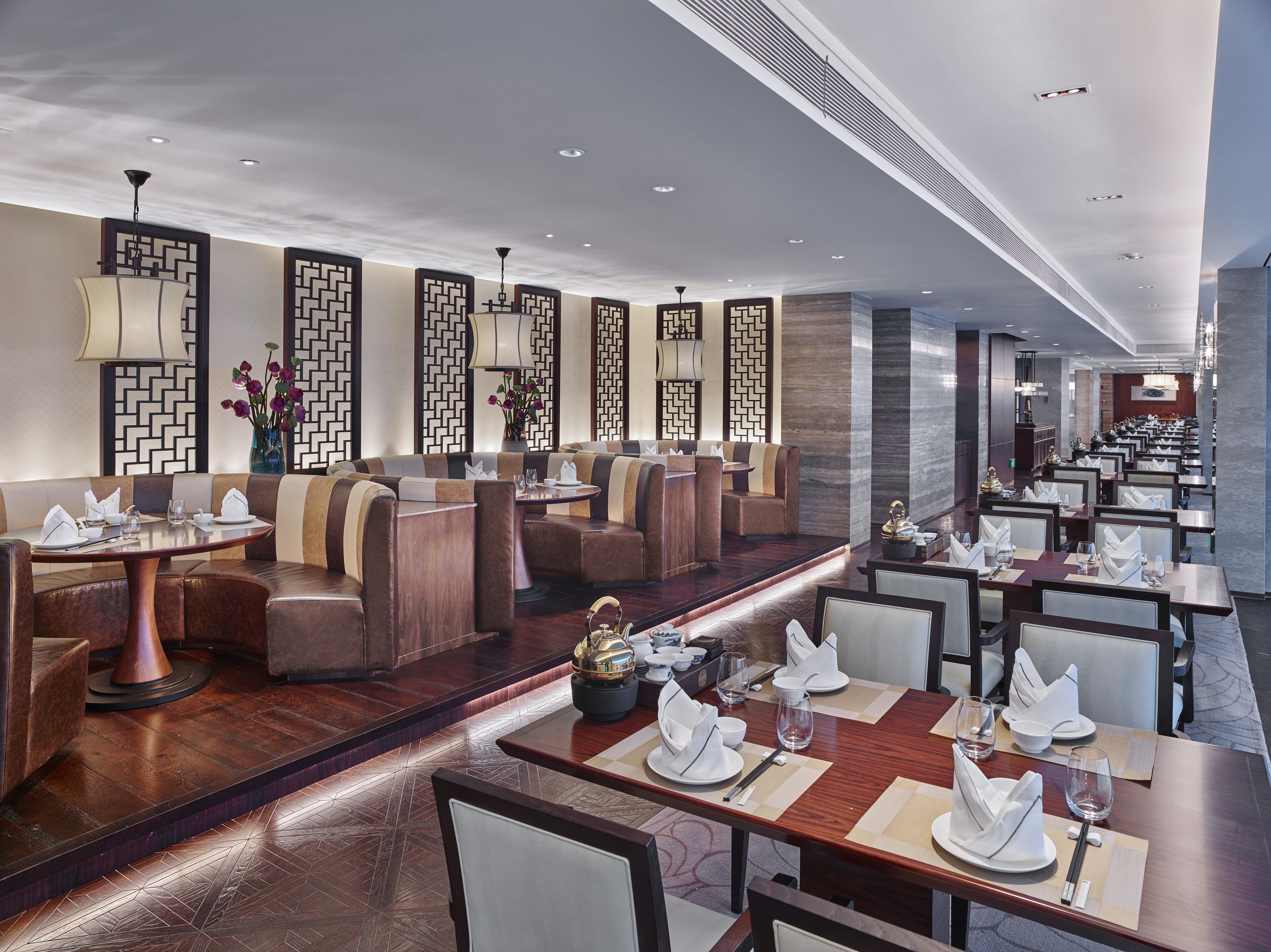 A modern restaurant with high tables and booths, decorative wall panels, and recessed lighting.