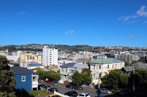 Un paisaje urbano con una combinación de edificios residenciales y comerciales, incluyendo un edificio blanco destacado con techo verde y un edificio azul con techo oscuro.