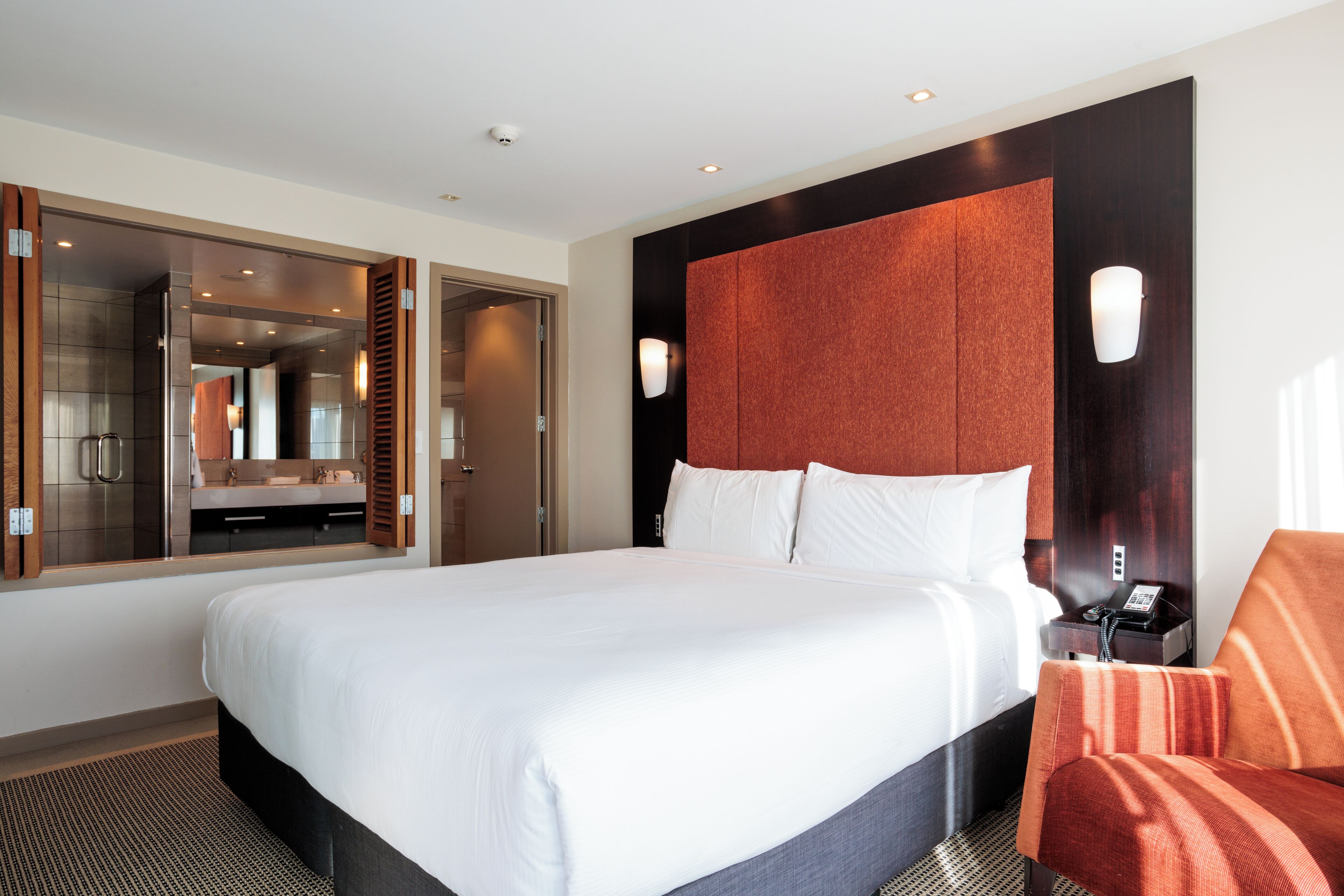 Ett hotellrum med en stor säng, ett badrum med en spegel och en sittgrupp.