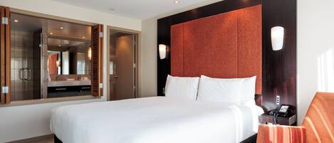 Habitación de hotel con una cama grande, un baño con espejo y una zona de estar.