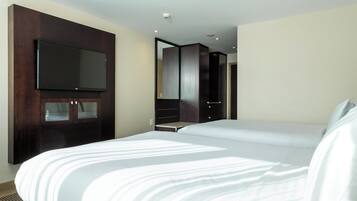 Habitación de hotel con una cama grande, un televisor de pantalla plana montado en un mueble de madera y un espejo en la pared.