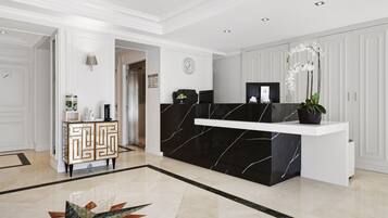 Un espace d’accueil doté d’un comptoir en marbre noir, d’une console blanche et d’un meuble orné de motifs géométriques.