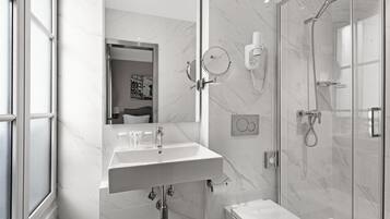 Ein modernes Badezimmer mit Marmorwaschtisch, einer gläsernen Duschkabine und einer Toilette.