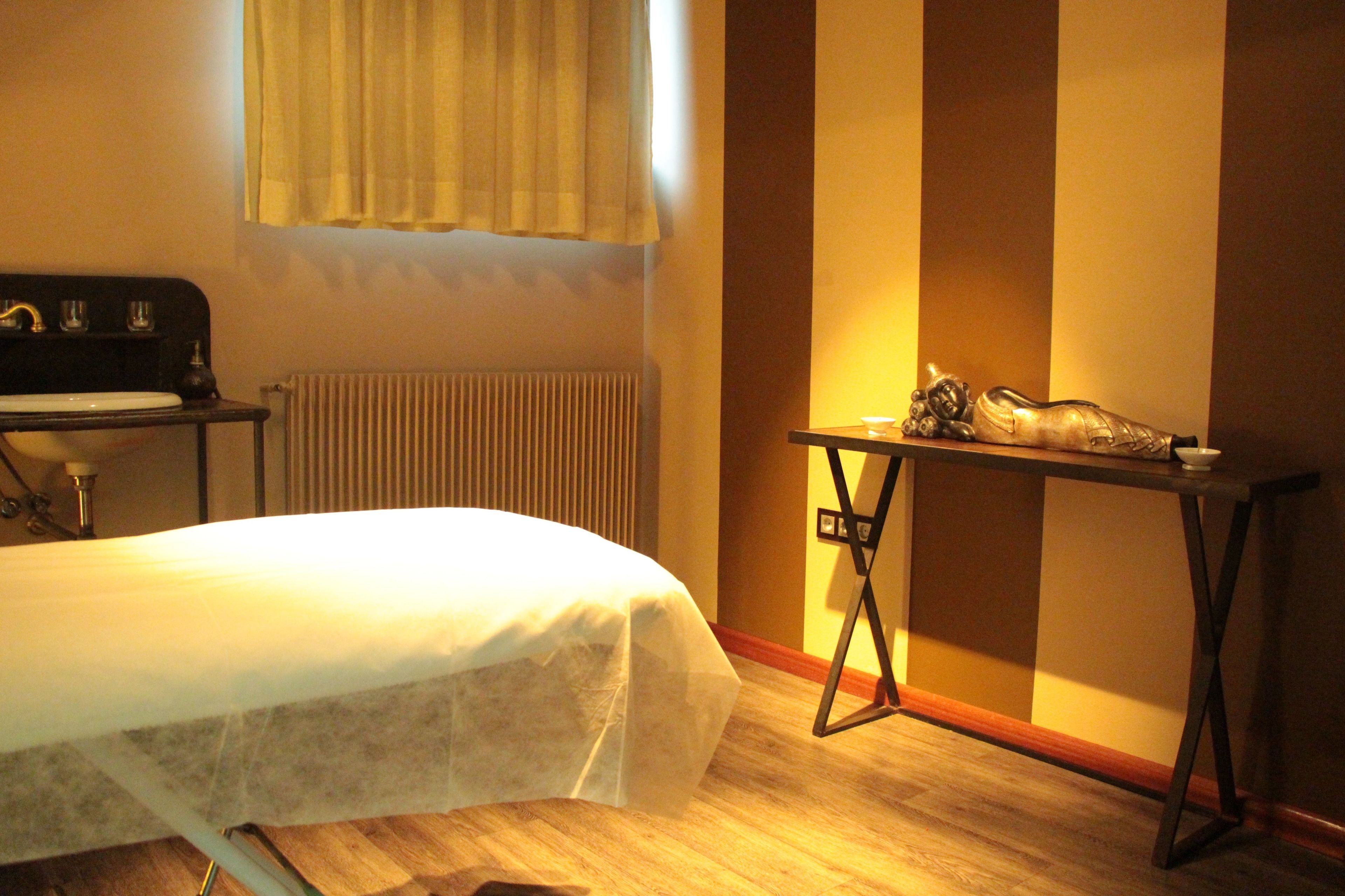A room with a bed, a table, a radiator, and a window with curtains.