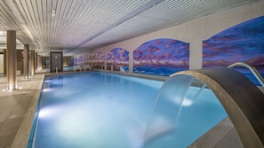 A swimming pool with a modern design, including a unique water feature and a mural depicting a sunset over mountains.