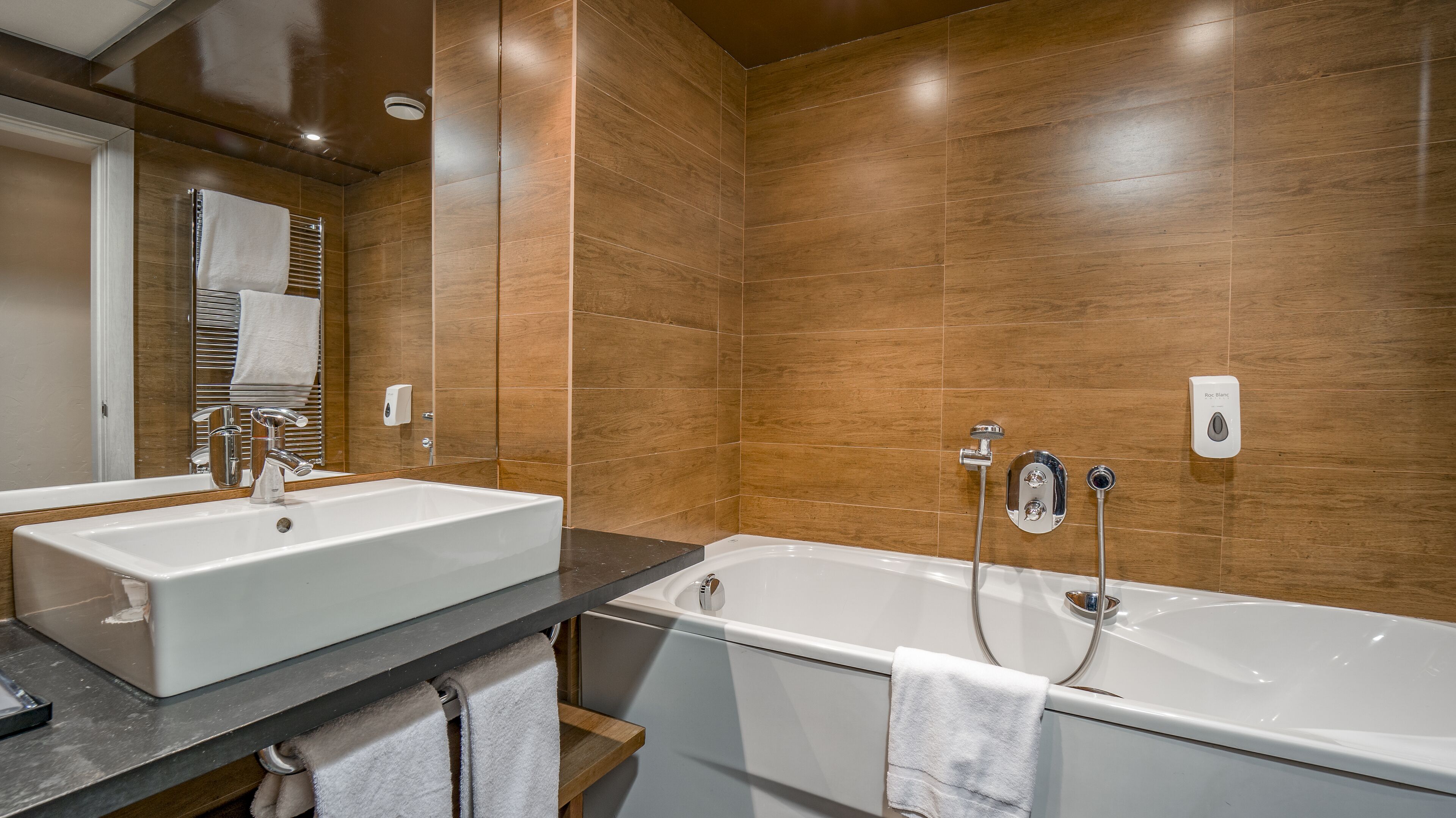Une salle de bain moderne avec une grande baignoire, un meuble-lavabo à deux vasques et un miroir.