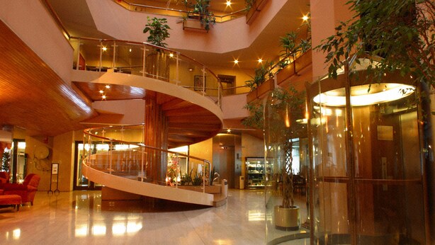 Un hall d’entrée spacieux doté d’un escalier en colimaçon central, de plusieurs niveaux et de plantes d’intérieur.