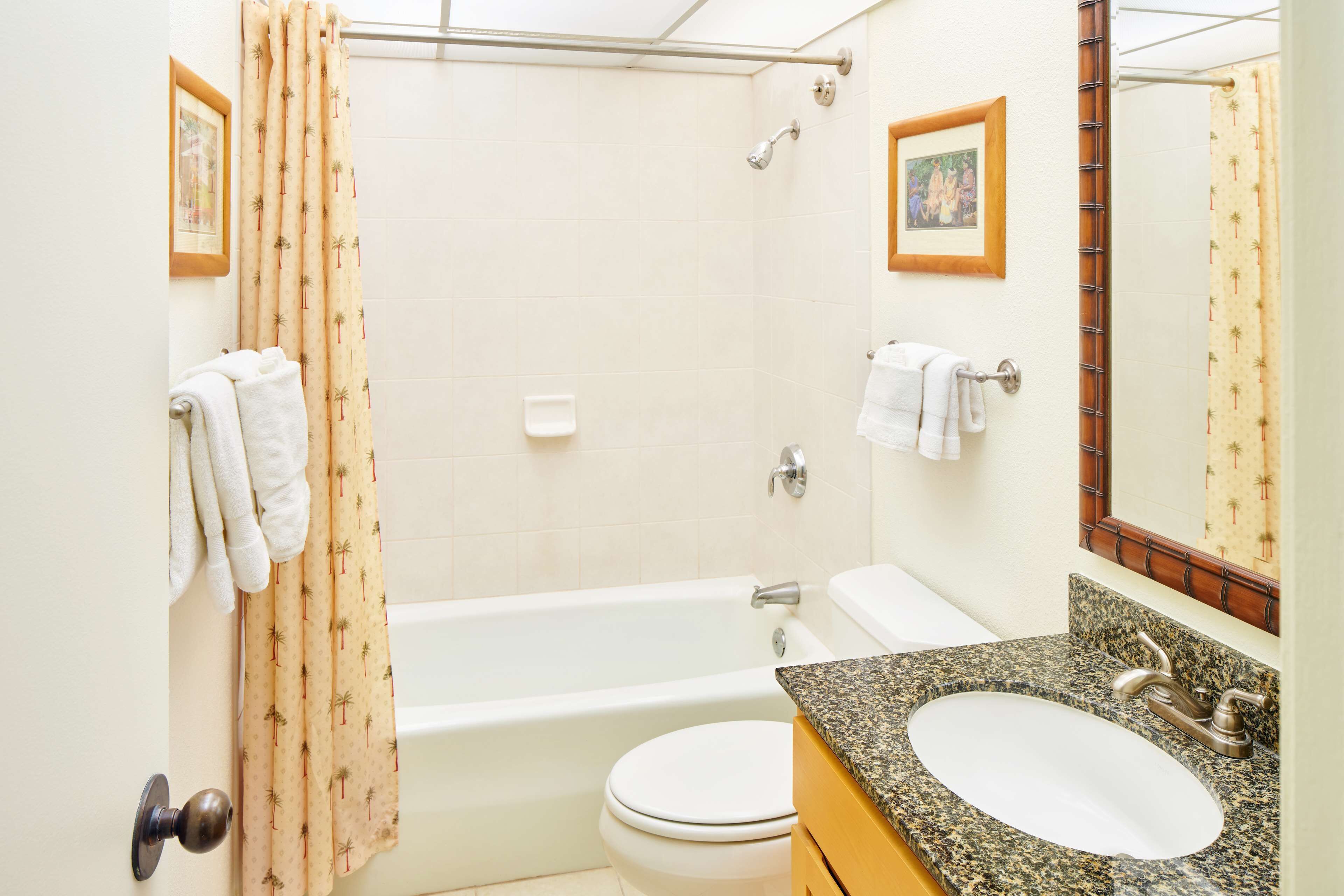 Un baño con bañera, inodoro, lavamanos y cortina de ducha.