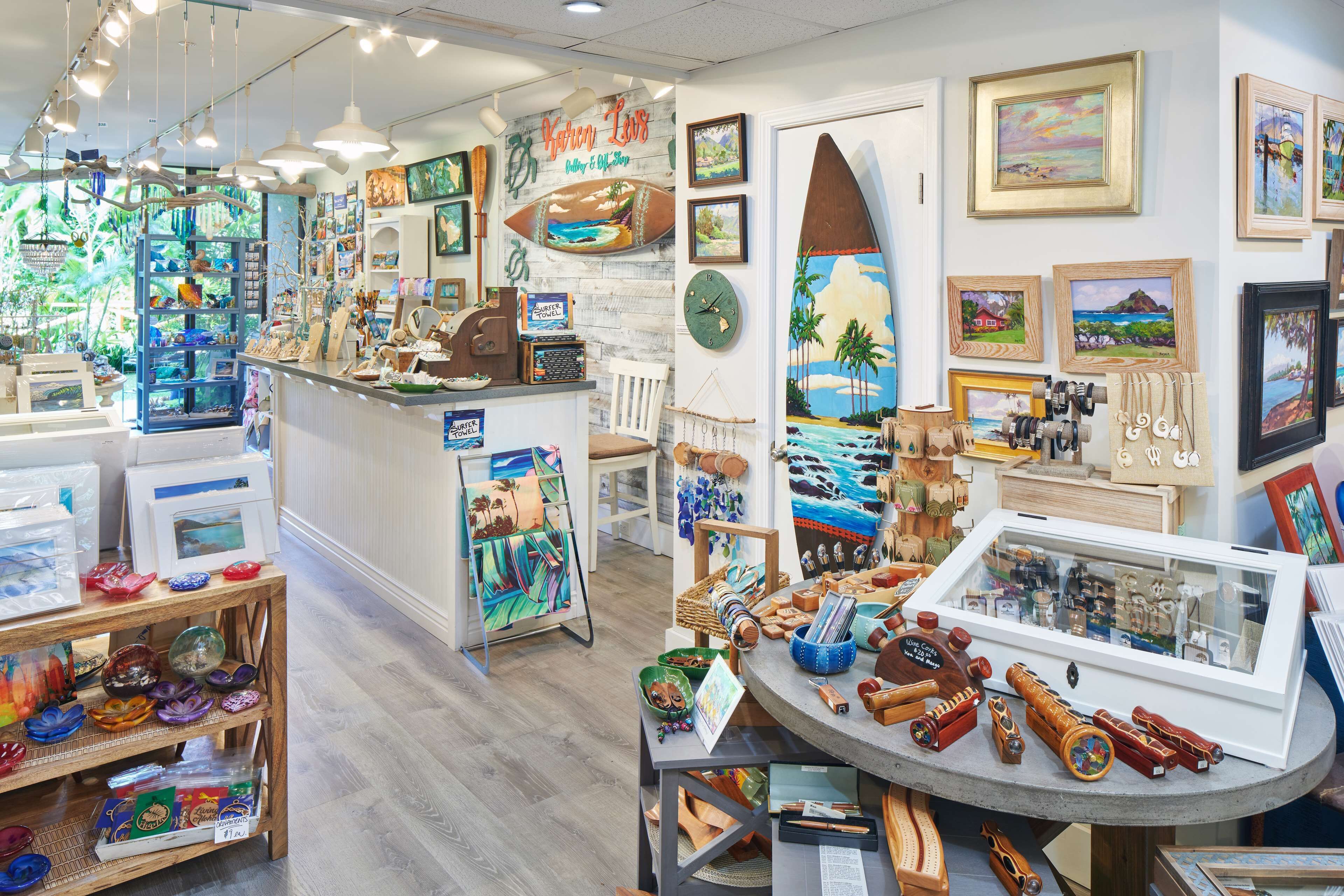 A well-lit art gallery with various paintings and sculptures displayed on shelves and tables.