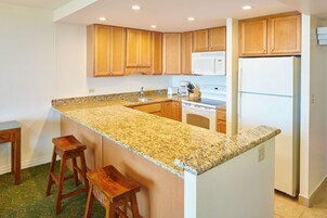 Una cocina con armarios de madera, encimera de granito, refrigerador de acero inoxidable y horno integrado.