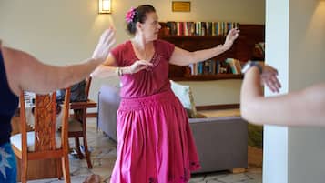 Una persona con un vestido rosa bailando en una habitación con una silla de madera, un sofá y una estantería al fondo.