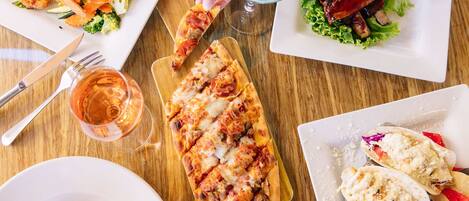 A variety of dishes including pizza, ribs, and tacos on a wooden table.