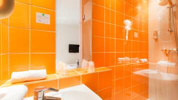A bathroom with orange tiles, a white sink, a mirror, and a shower area.
