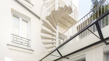 Un edificio moderno con una escalera de caracol, una puerta de vidrio y una terraza de madera.