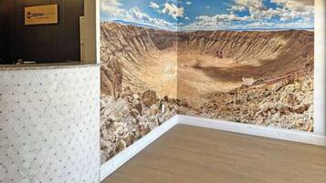 Un área de recepción con un mural panorámico de un cañón, una mesa de recepción y piso de madera.