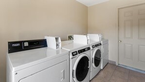 A laundry room with a Maytag commercial washer and dryer, a control panel, and a door. - SureStay by Best Western Lakeview (Lakeview)