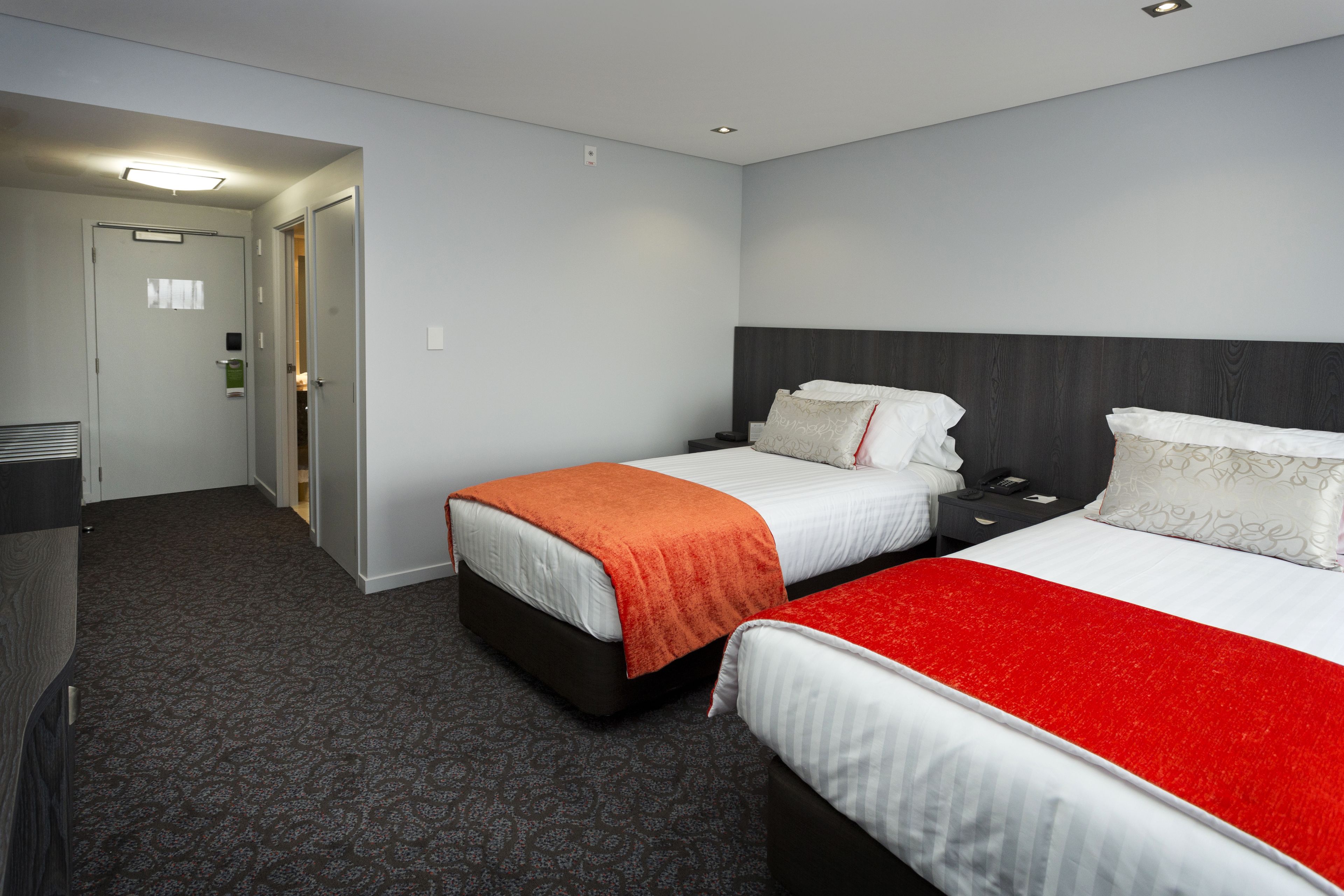 Een hotelkamer met twee bedden, een bureau en een stoel.