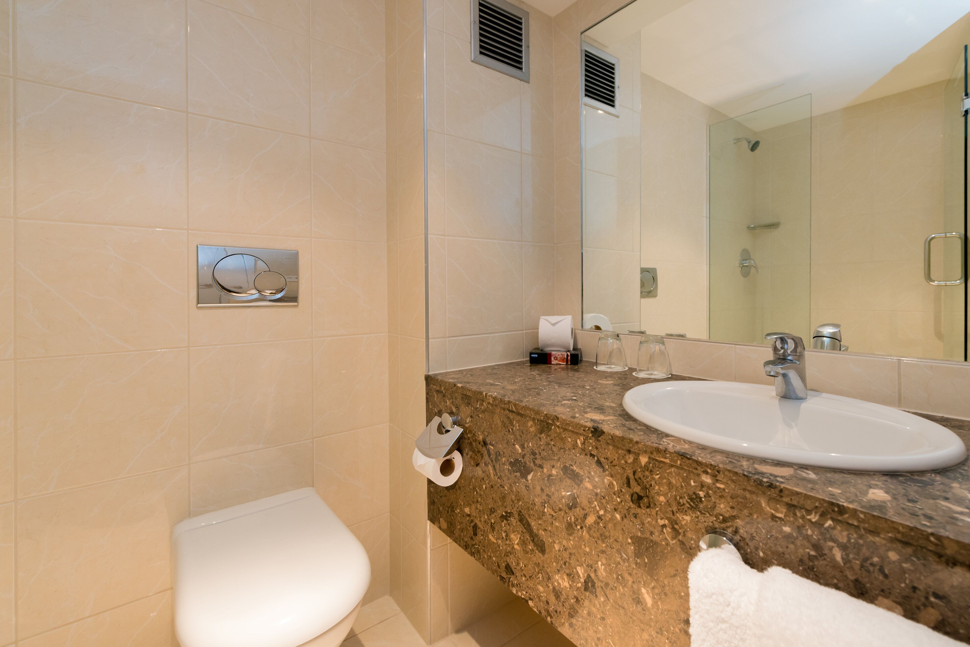 A bathroom with a toilet, sink, mirror, and towel.