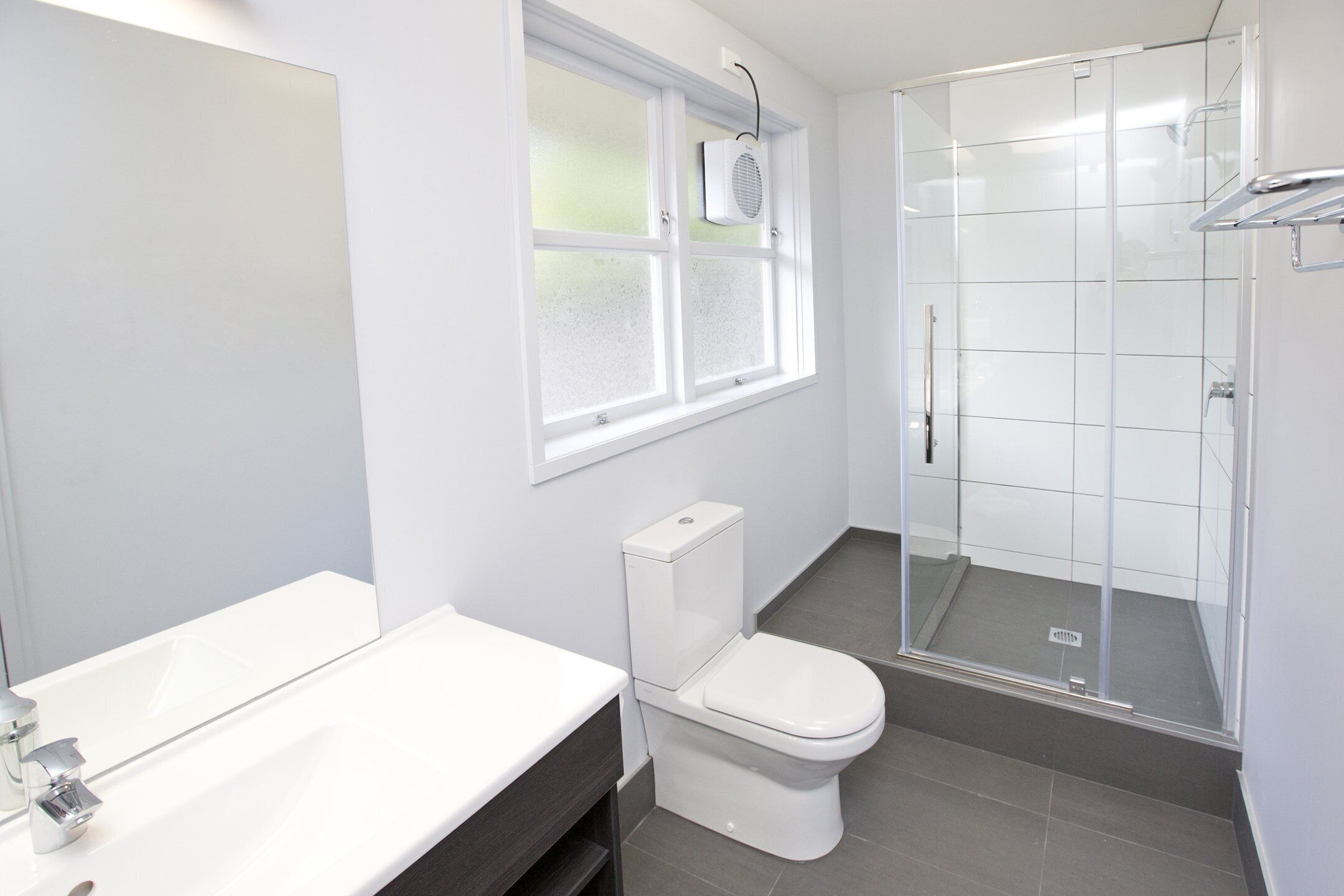 A modern bathroom with a white sink, toilet, and shower.