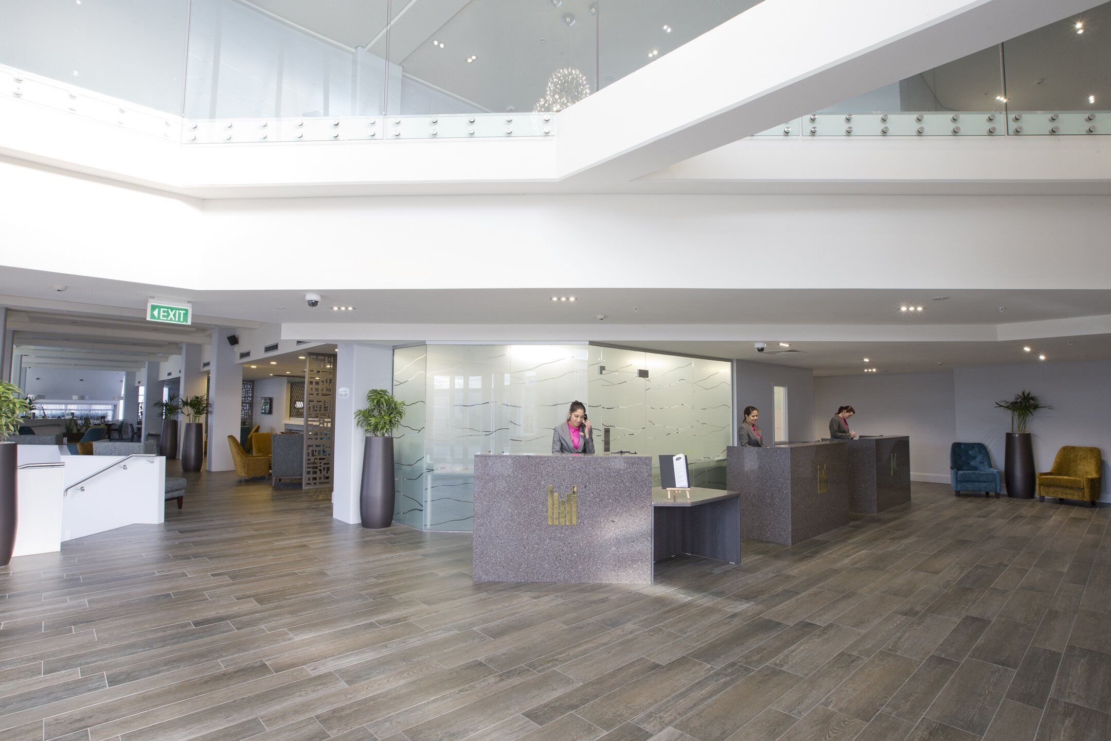 A spacious lobby with a reception desk, seating area, and a staircase leading to an upper level.