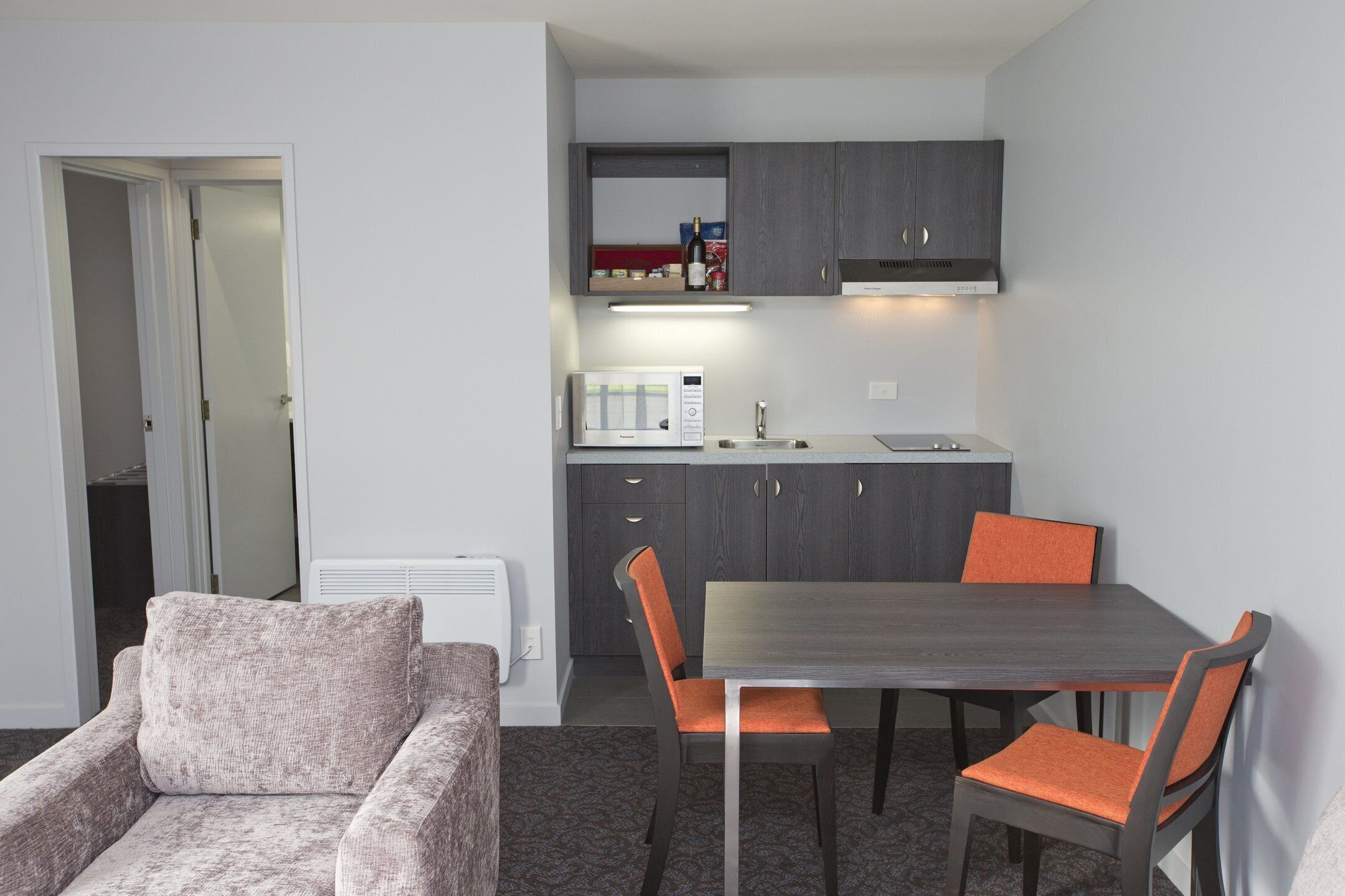 A compact living space with a kitchenette, a dining area with a table and chairs, and a sofa.
