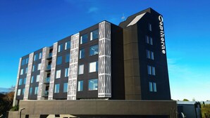 A modern hotel with a unique facade featuring vertical white patterns, multiple balconies, and large windows. - Copthorne Hotel Palmerston North (Palmerston North)
