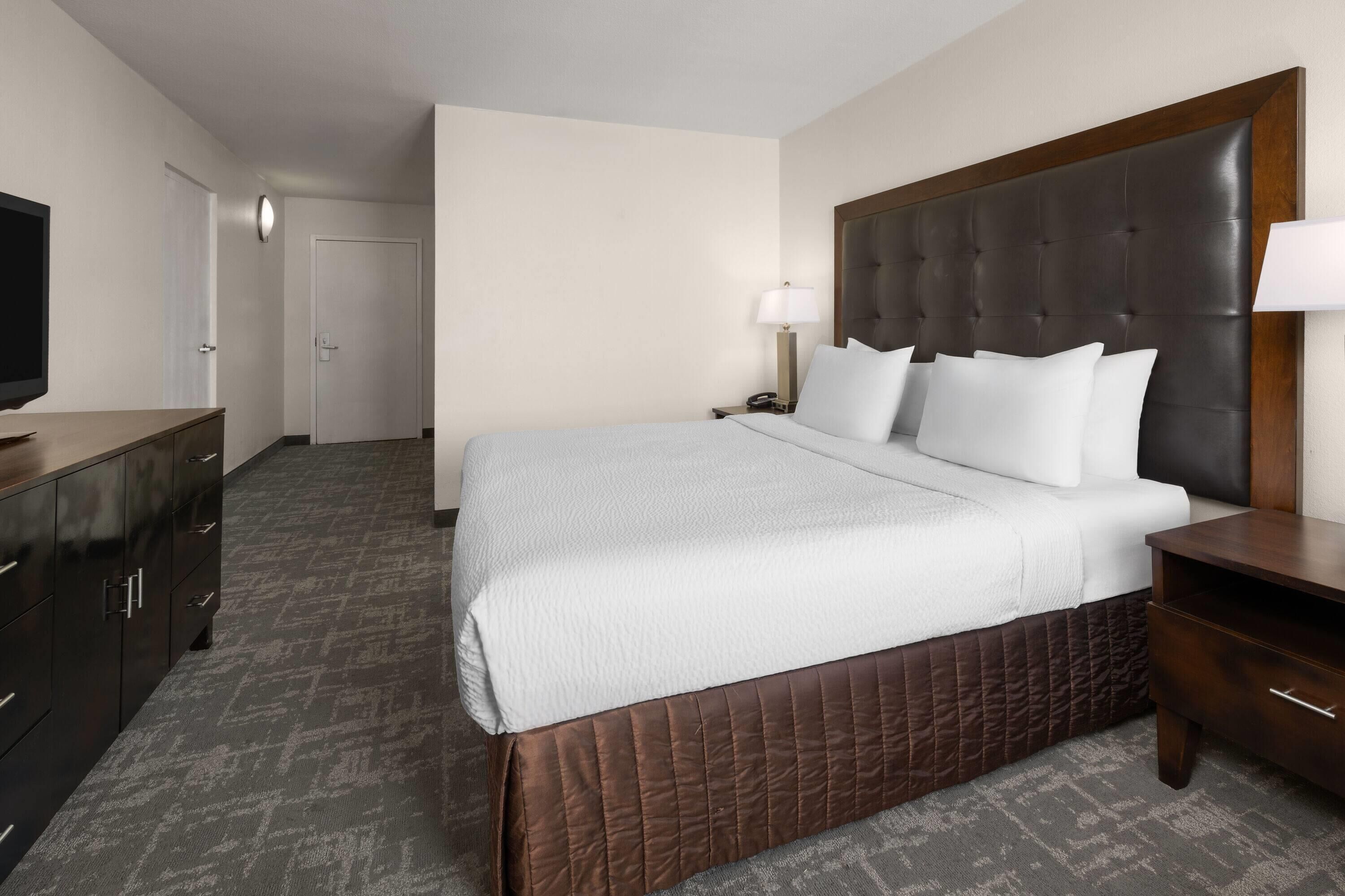A hotel room with a bed, a TV, a desk, and a wardrobe.