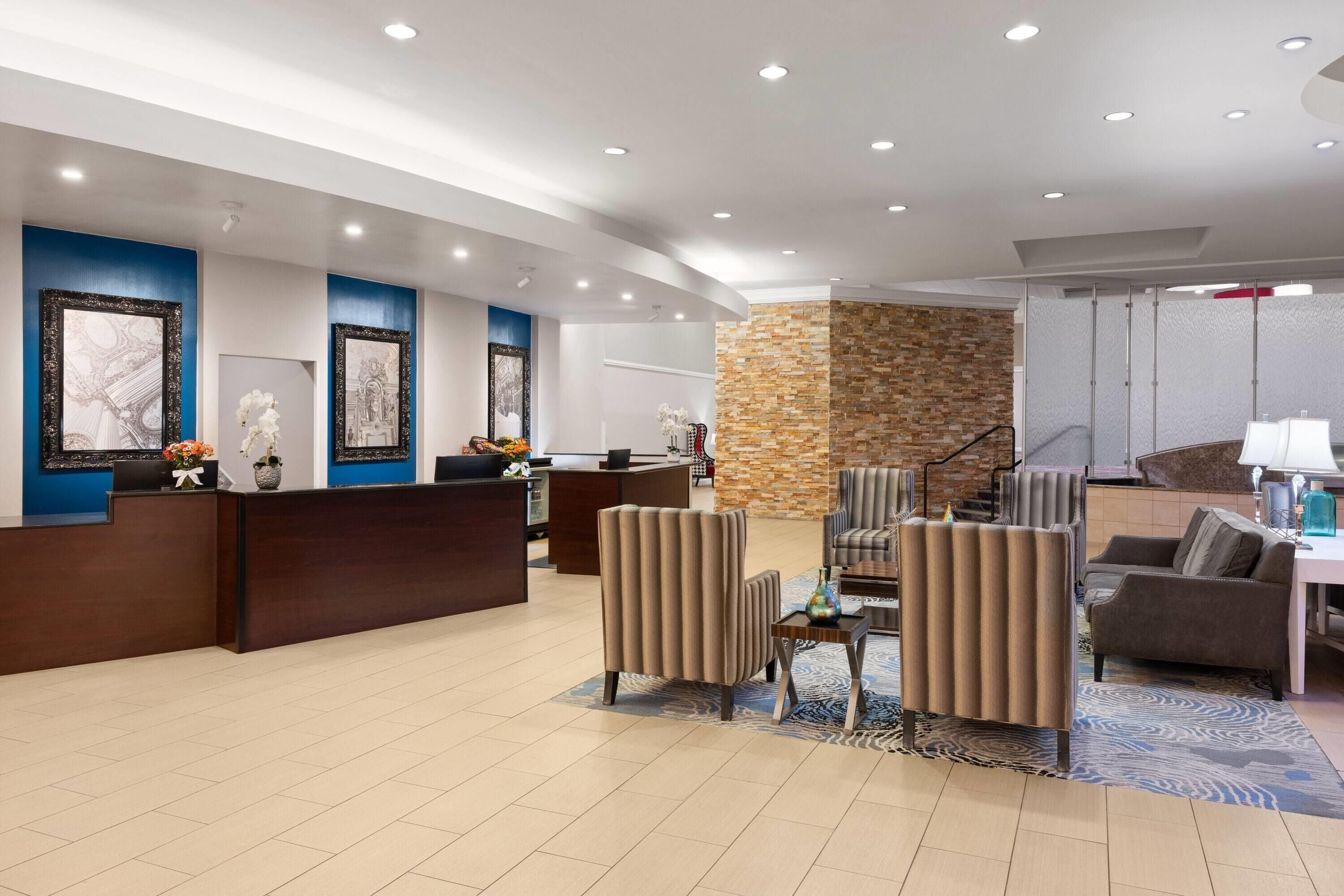 A hotel lobby with a reception desk, seating area, and a stone accent wall.