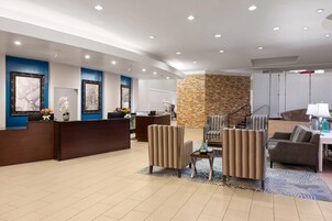 Vestíbulo de hotel con mostrador de recepción, zona de estar y una pared de acento de piedra.
