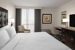 A hotel room with a large bed, a desk, a chair, a television, and a window with curtains. - Wyndham Sacramento (Sacramento)