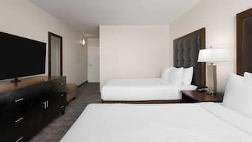 Una habitación de hotel con dos camas, un televisor, un escritorio y una lámpara.