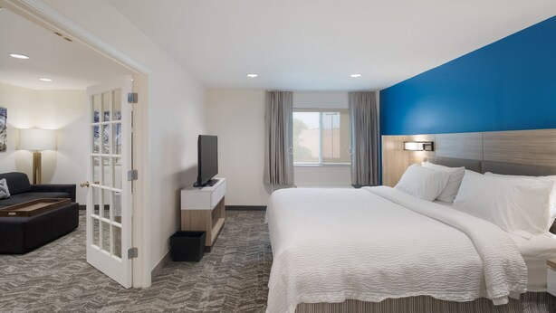 A hotel room with a bed, a TV, a desk, and a seating area. - SpringHill Suites by Marriott Dallas NW Hwy/I35E (Dallas)