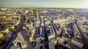 An aerial view of a cityscape with a mix of modern and historic buildings, a prominent church, and a river in the background. - ibis Styles Nantes Centre Place Royale (Nantes)