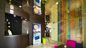 Un espace d’accueil comprenant un comptoir, des chaises, un décor mural coloré et une affiche.