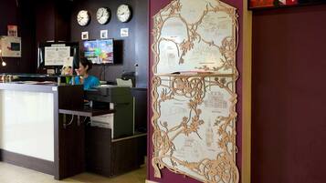 Una mesa de recepción con un monitor, un reloj y una pared con un mapa detallado.