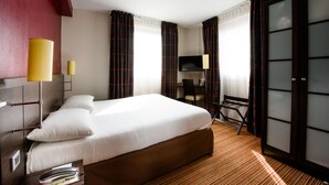 Une chambre d’hôtel avec un grand lit, un bureau, une chaise, une télévision et une porte coulissante.