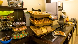 Un buffet proposant une variété de plats, notamment du pain, des pâtisseries et des condiments.