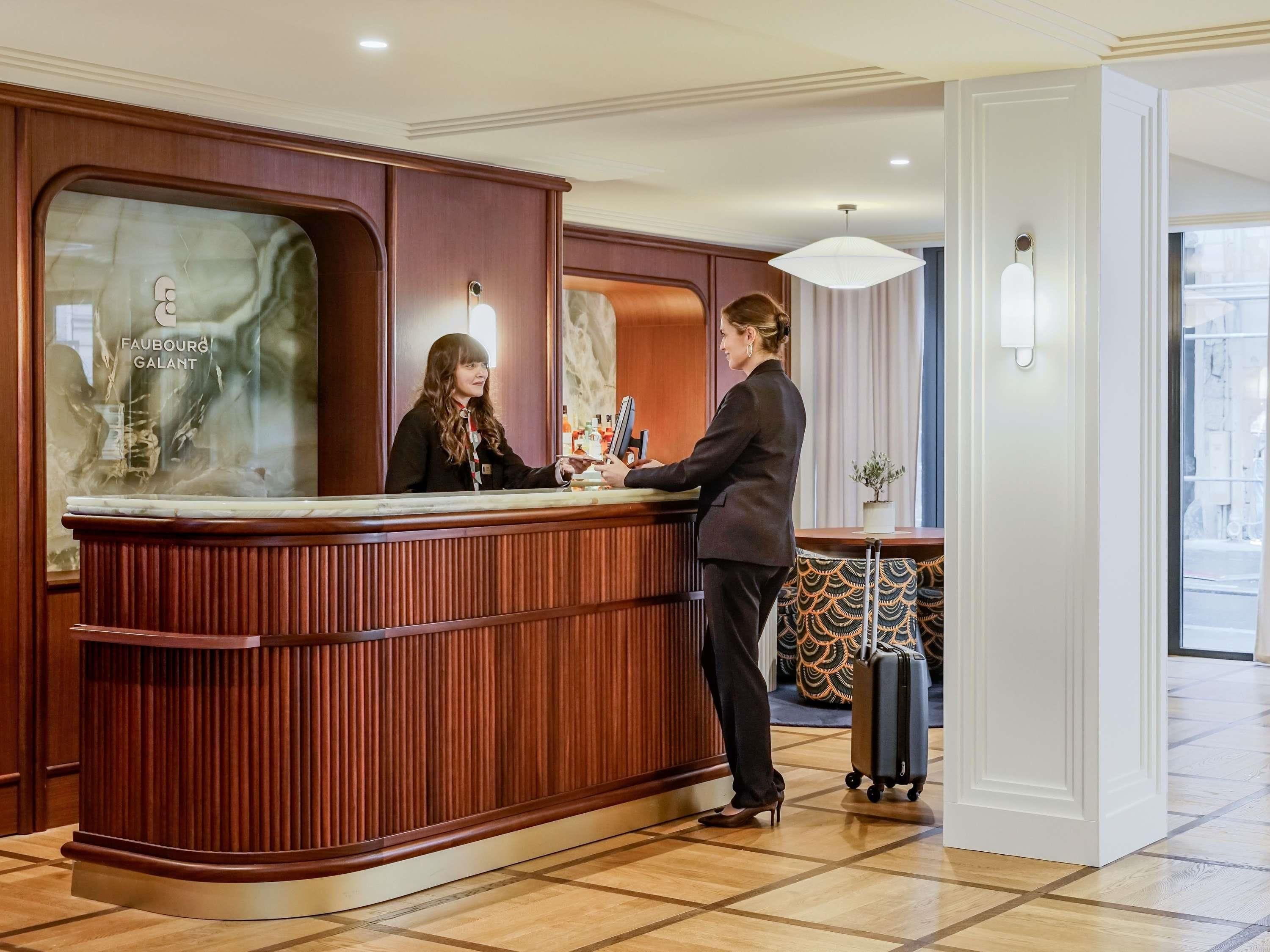 Un mostrador de recepción con detalles de madera y una ventana de vidrio que muestra el nombre del hotel.