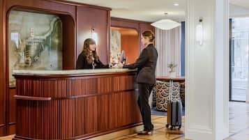 Un mostrador de recepción con detalles de madera y una ventana de vidrio que muestra el nombre del hotel.