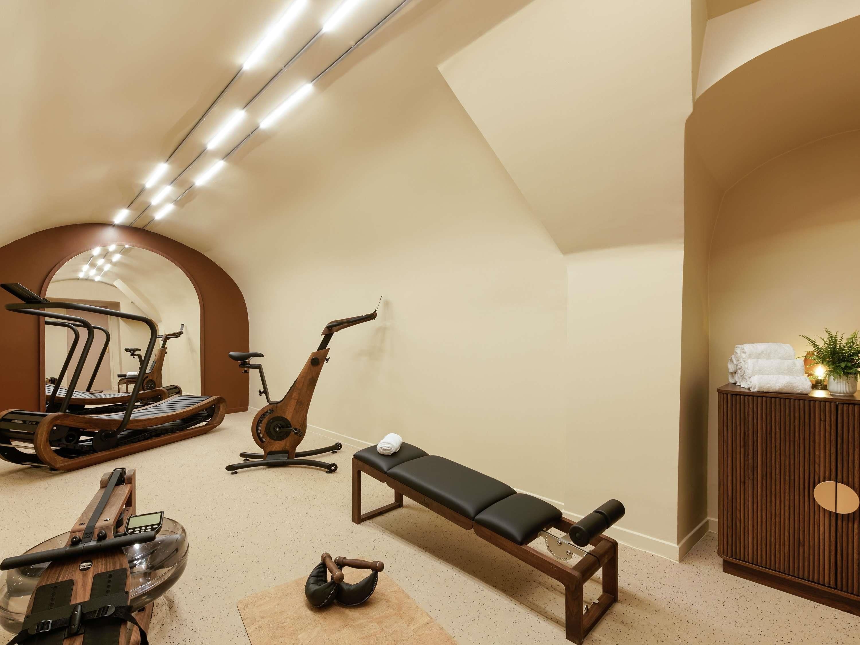 Ett gym med träningsutrustning, inklusive löpband, motionscykel, roddmaskin och en träningsbänk.