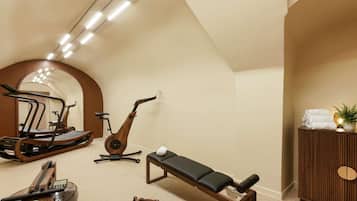 Ett gym med träningsutrustning, inklusive löpband, motionscykel, roddmaskin och en träningsbänk.