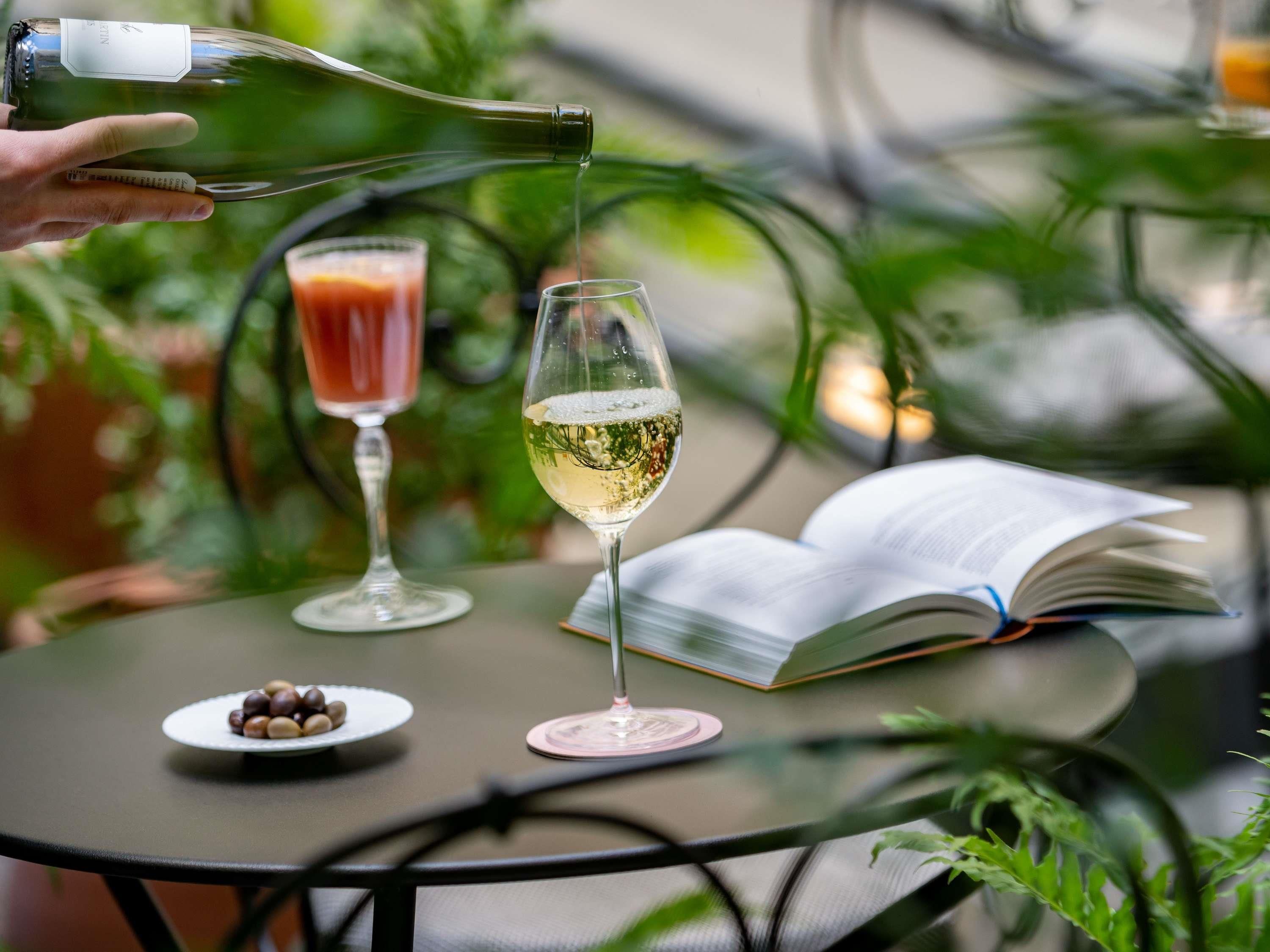 Une table avec un livre, deux verres de boissons et une assiette de noix.
