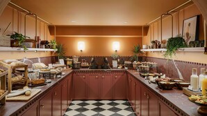 A kitchen with a checkered floor, wooden cabinets, and various food items displayed on counters. - Hotel Faubourg Galant Paris - Handwritten Collection (Paris)
