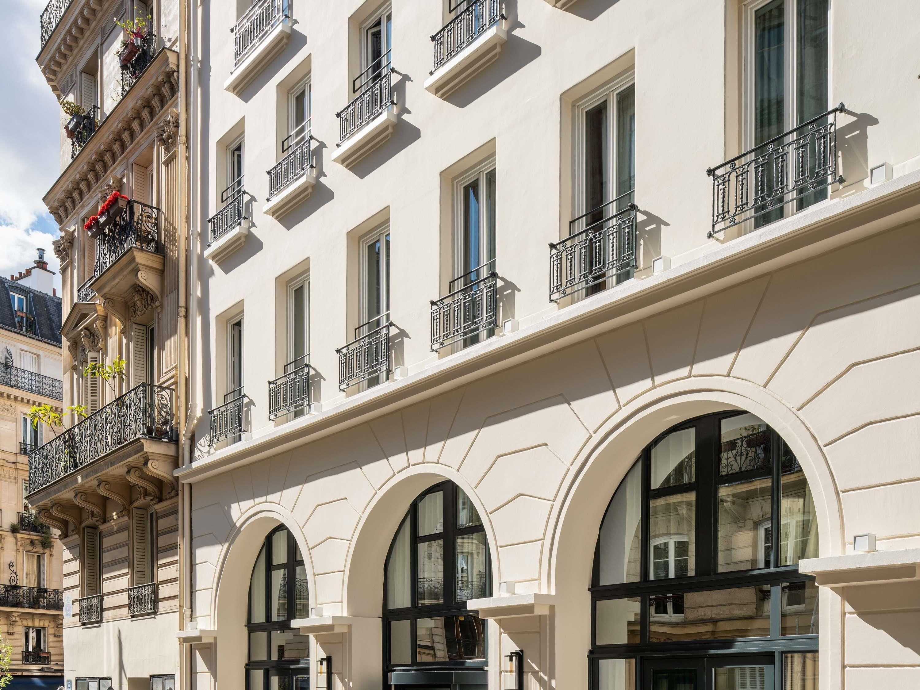 Um edifício de vários andares com janelas em arco e varandas com grades de ferro forjado.