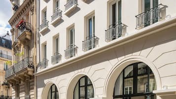 Um edifício de vários andares com janelas em arco e varandas com grades de ferro forjado.