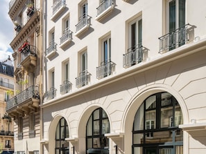 A multi-story building with arched windows and balconies with wrought iron railings. - Hotel Faubourg Galant Paris - Handwritten Collection (Paris)