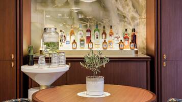 Un área de bar con una mesa redonda, sillas y una variedad de botellas.