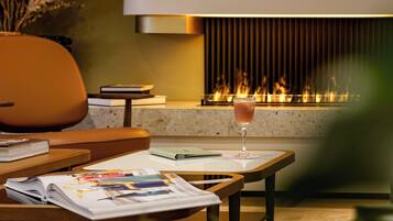 Una sala de estar moderna con chimenea, un sofá, una mesita de centro y una copa de bebida.